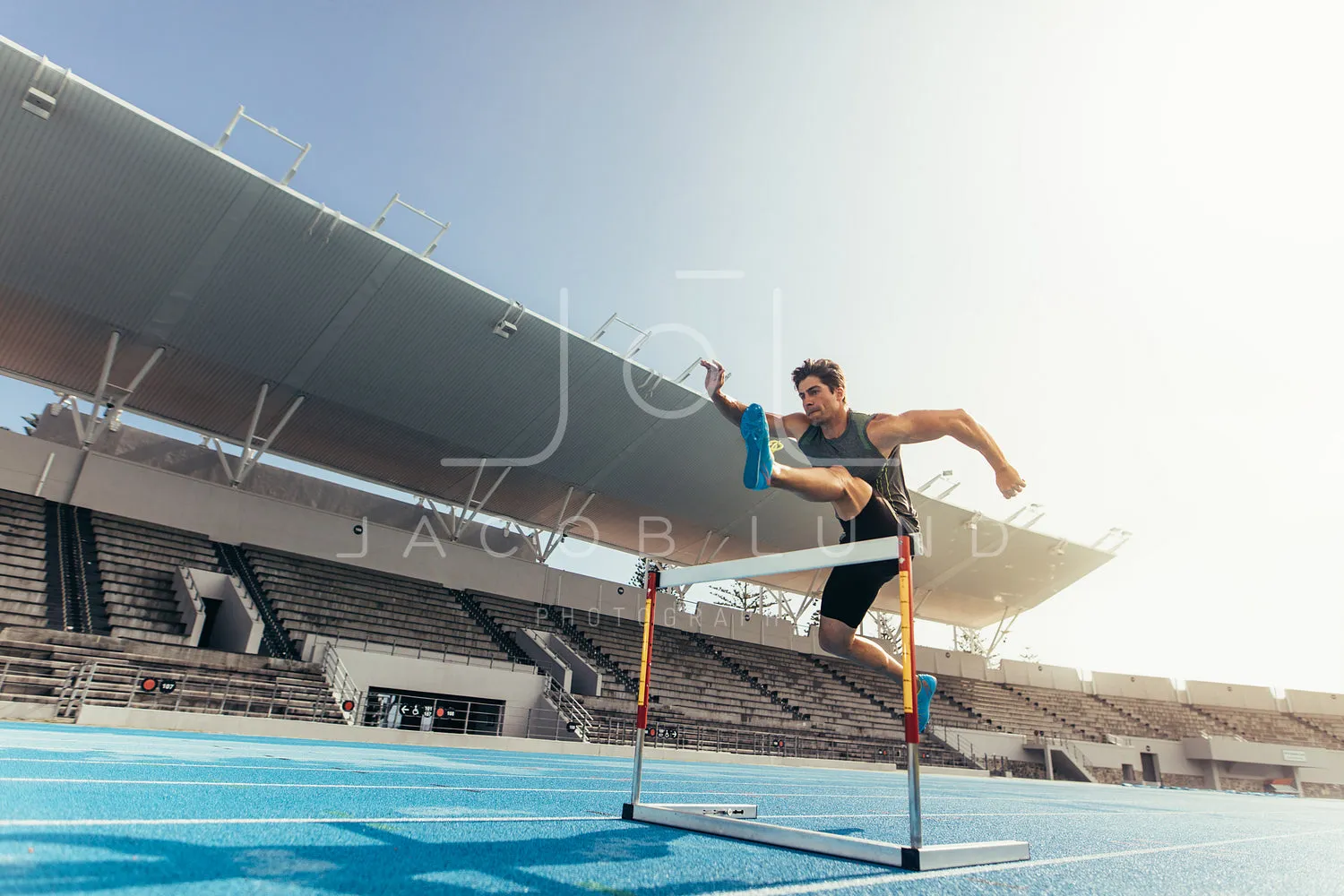 Athlete jumping over an hurdle on running track